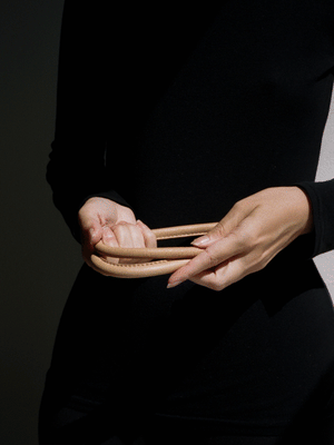 woman in all black outfit showing how to knot a leather belt