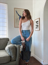woman in white aymmetric knit top and light blue denim pants