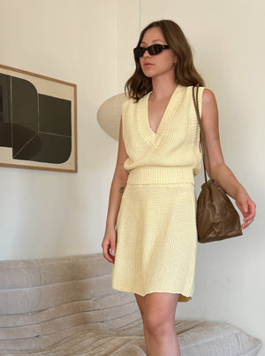 woman in matching yellow knitted vest and skirt set wearing black sunglasses and brown leather shoulder bag