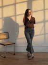 woman standing in brown silky short sleeve shirt and blue jeans
