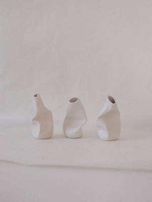 three small sculpted ceramic vases in white