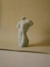 sideview of a woman body shaped candle in sage color