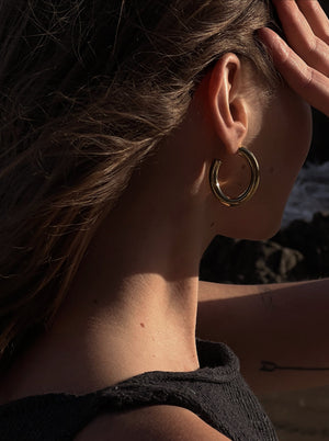 woman wearing gold hoop earring and black tank top